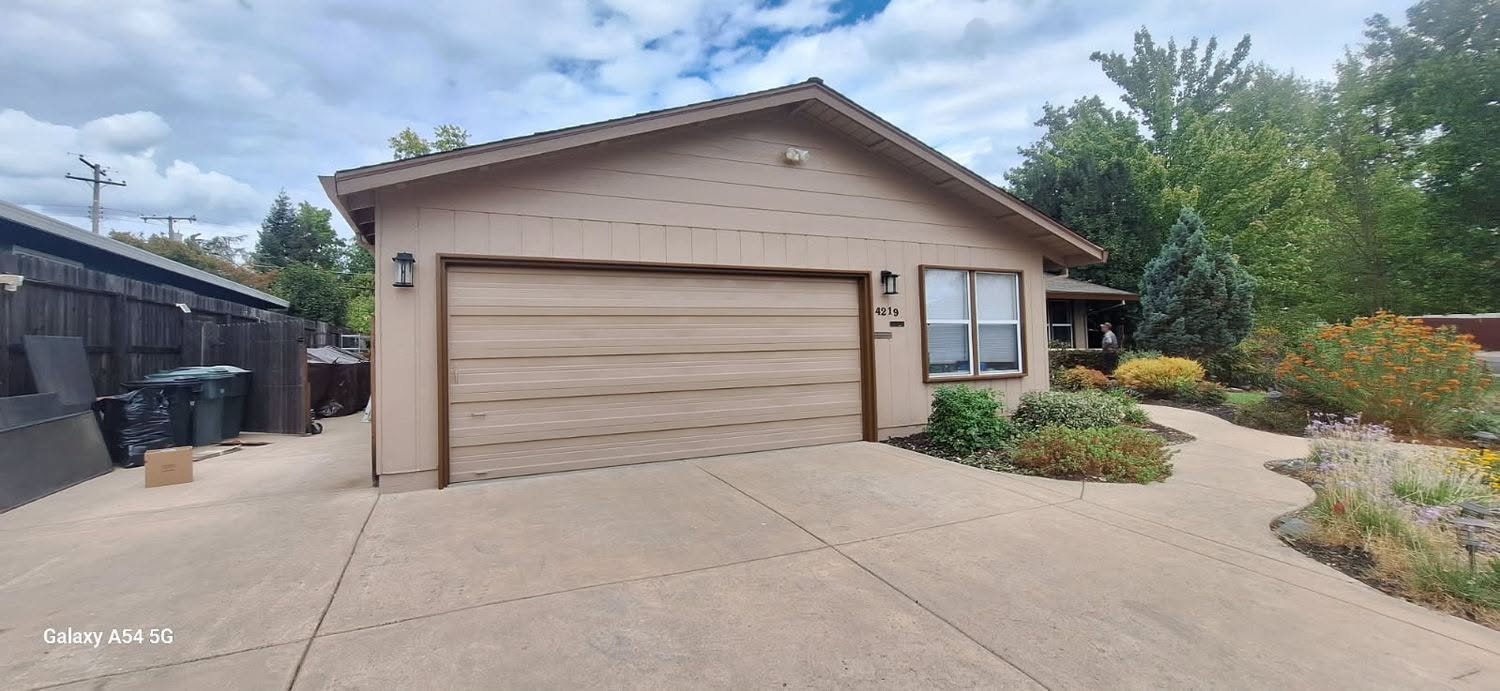 Tan ranch home with refreshed garage door and trim