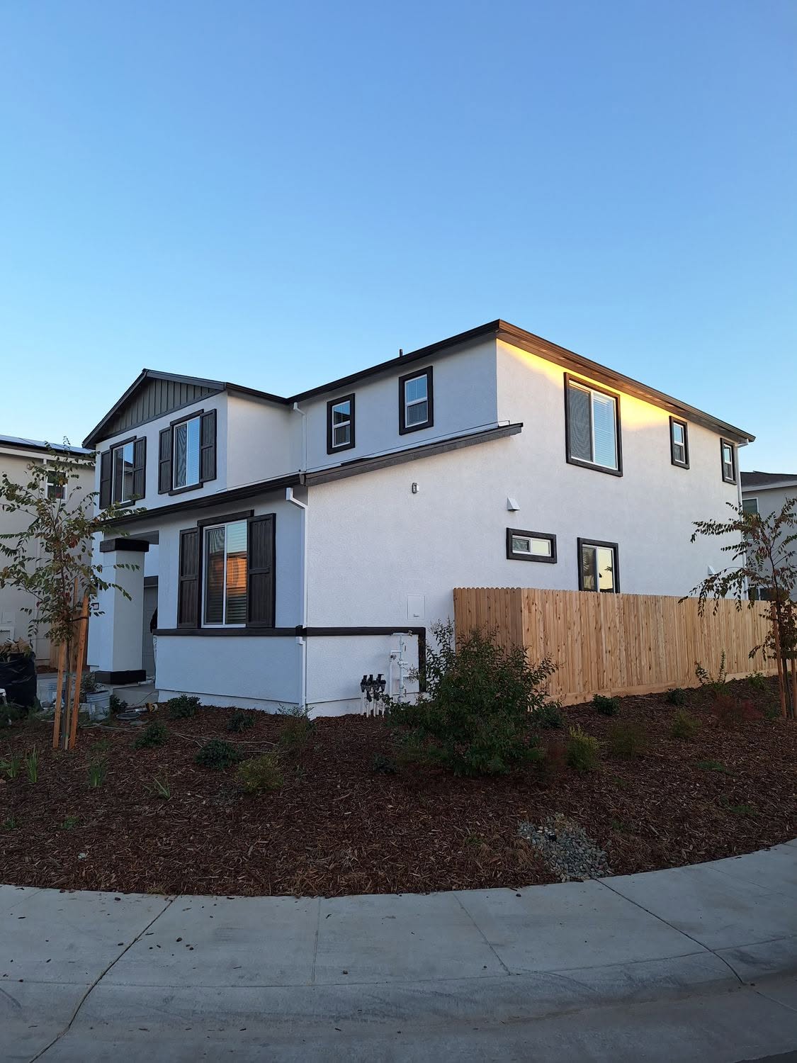 Modern white two-story with black trim photographed at dusk